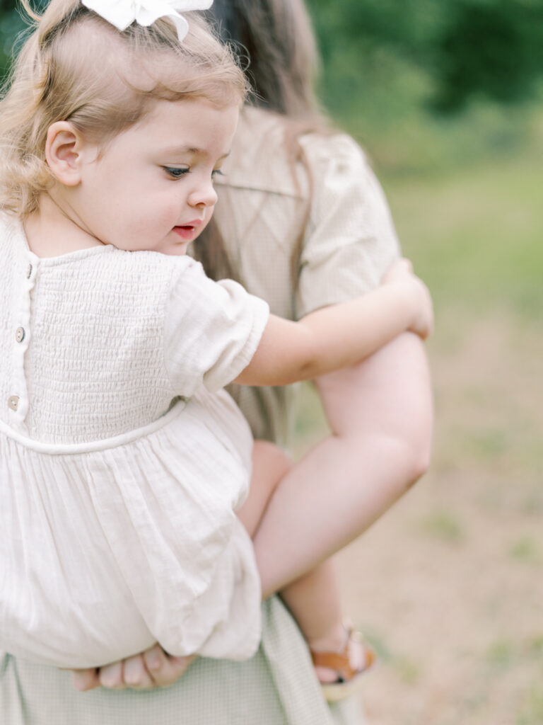 Detail shot of young daughter's arms wrapped around her mother's in a piggy back.