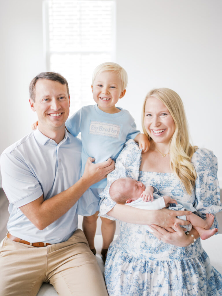 Joyful Little Rock family newborn session - big brother smiling while parents hold their newborn.