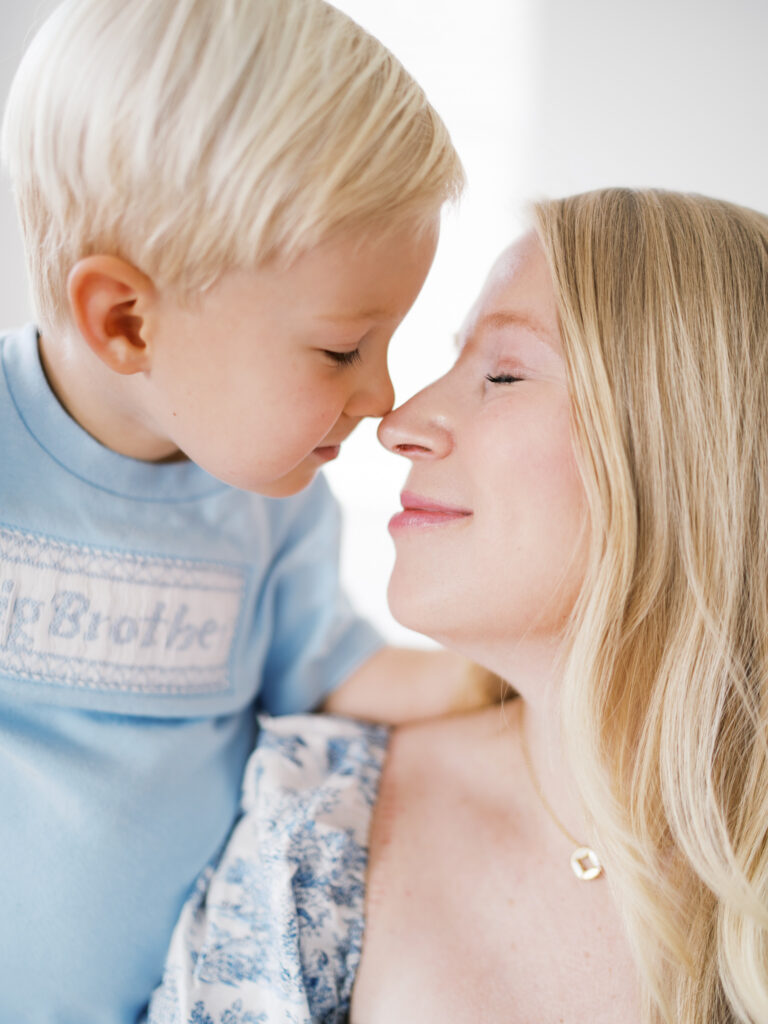 Sweet moment of mother and big brother sharing a nose-to-nose snuggle taken by Little Rock newborn photographer Bailey Feeler.