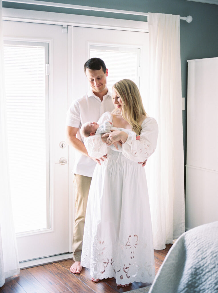 Parents holding their baby in soft natural light during a lifestyle family session, captured on film