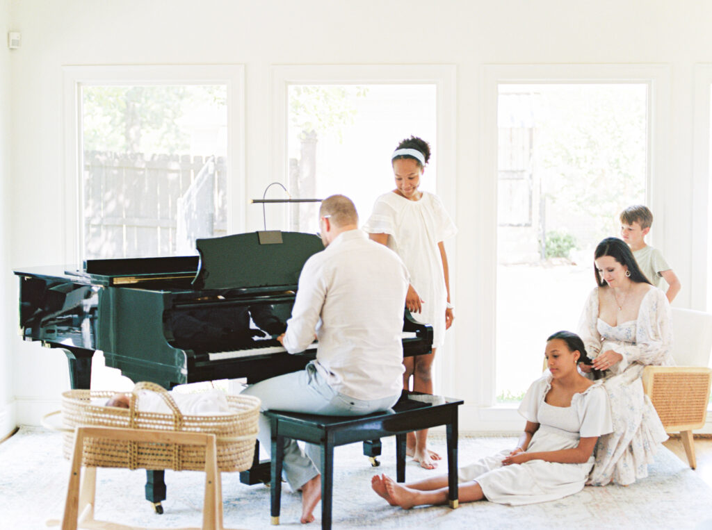Family gathered around a piano during a natural film lifestyle session with Bailey Feeler Photography, family photographer in Arkansas.