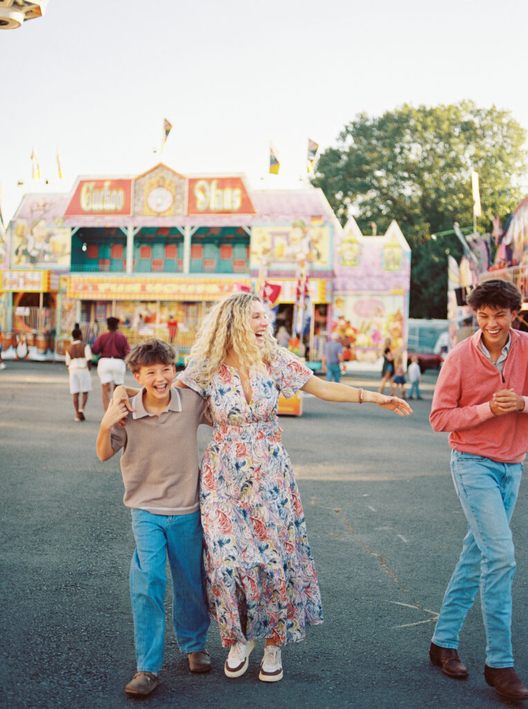 Mother with older children laughing together during a relaxed outdoor photo session at the state fair